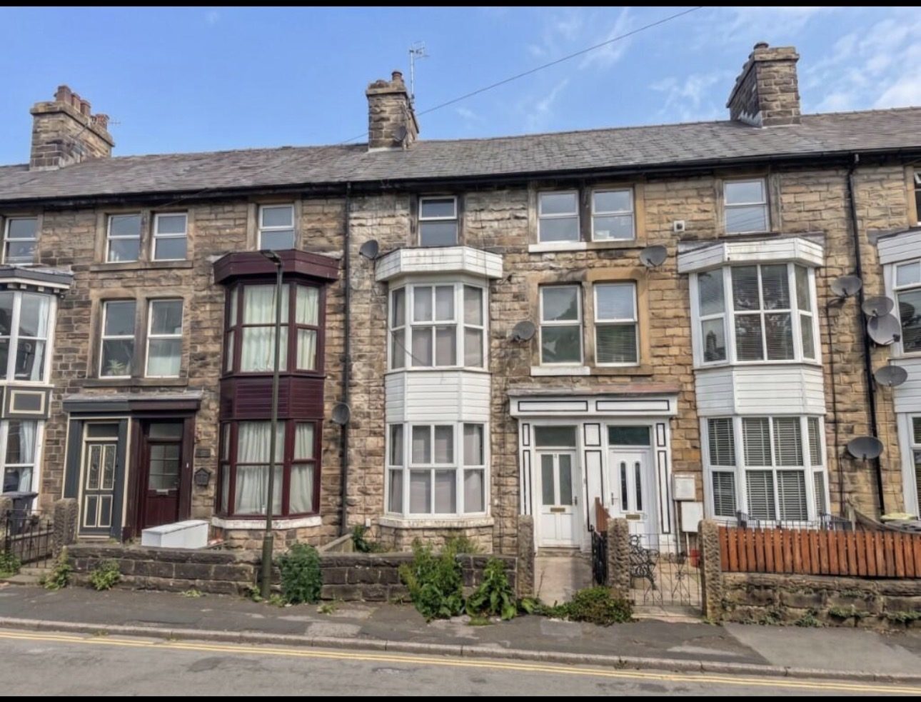 Stone-fronted Victorian terrace divided into flats, with original bay windows and visible deferred maintenance.