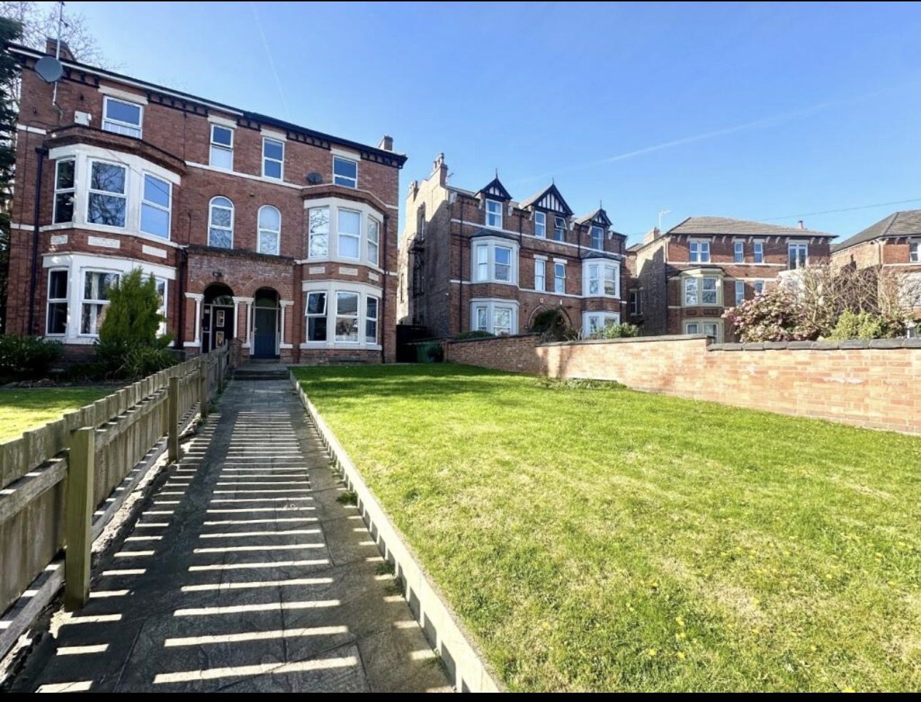 Red brick Victorian villas converted into self-contained flats, on a residential street in South Manchester.